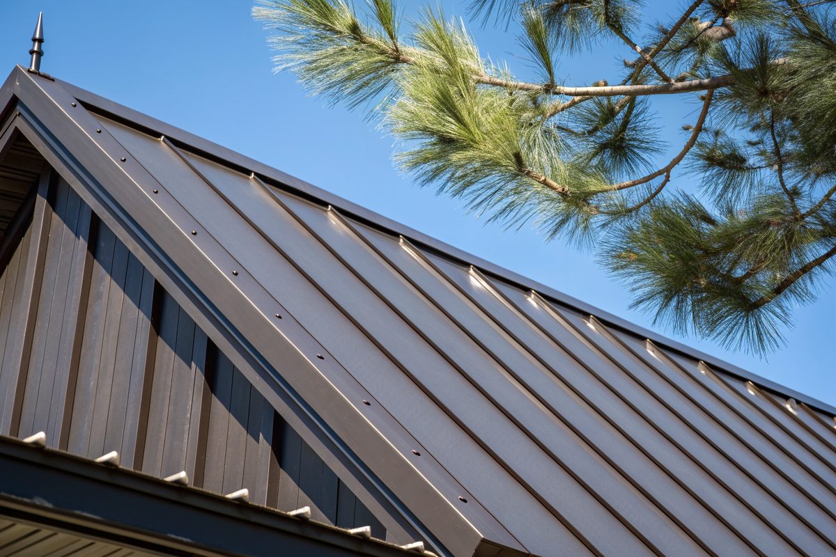 Close view of dark bronze standing-seam metal roof panels against a blue sky